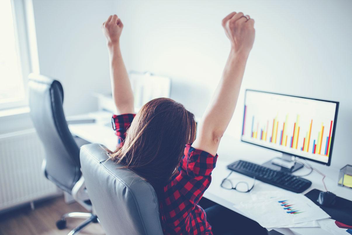 Woman looking at spreadsheet and raising her fists in celebration